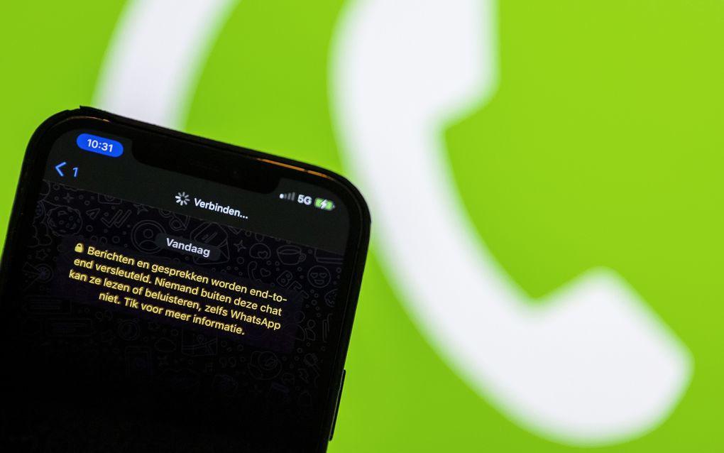 Het scherm van een smartphone met daarop berichtendienst Whatsapp tegen een groene achtergrond met het logo van Whatsapp.