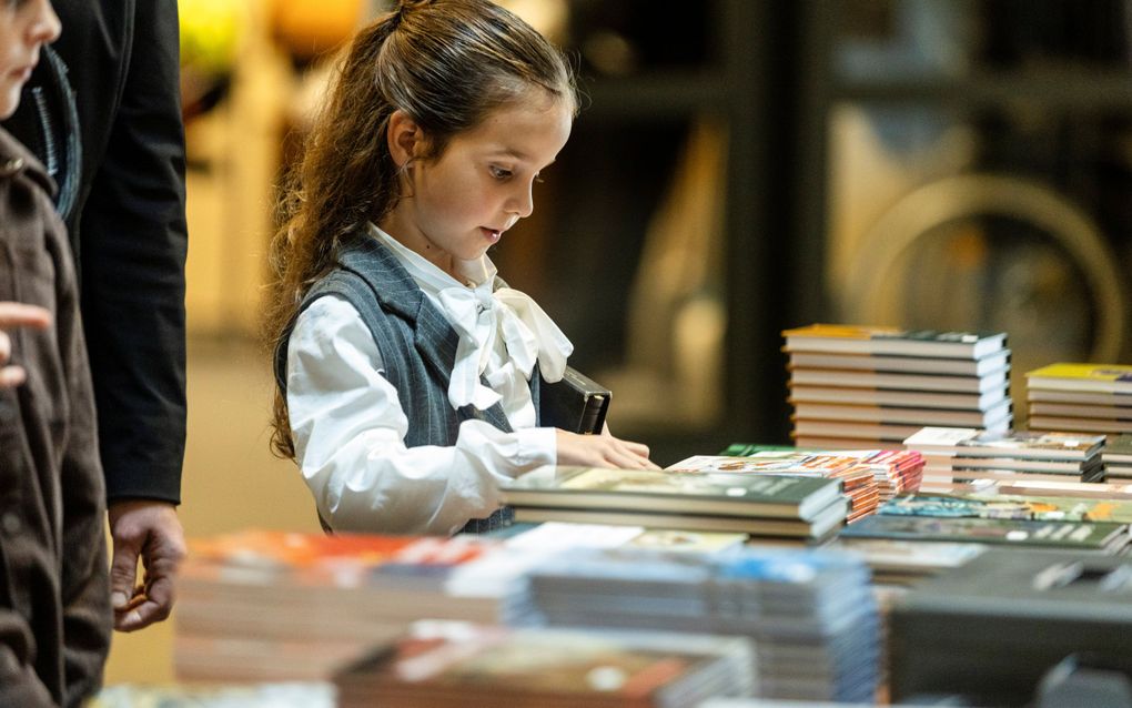 Meisje bekijkt boeken die op tafel liggen.