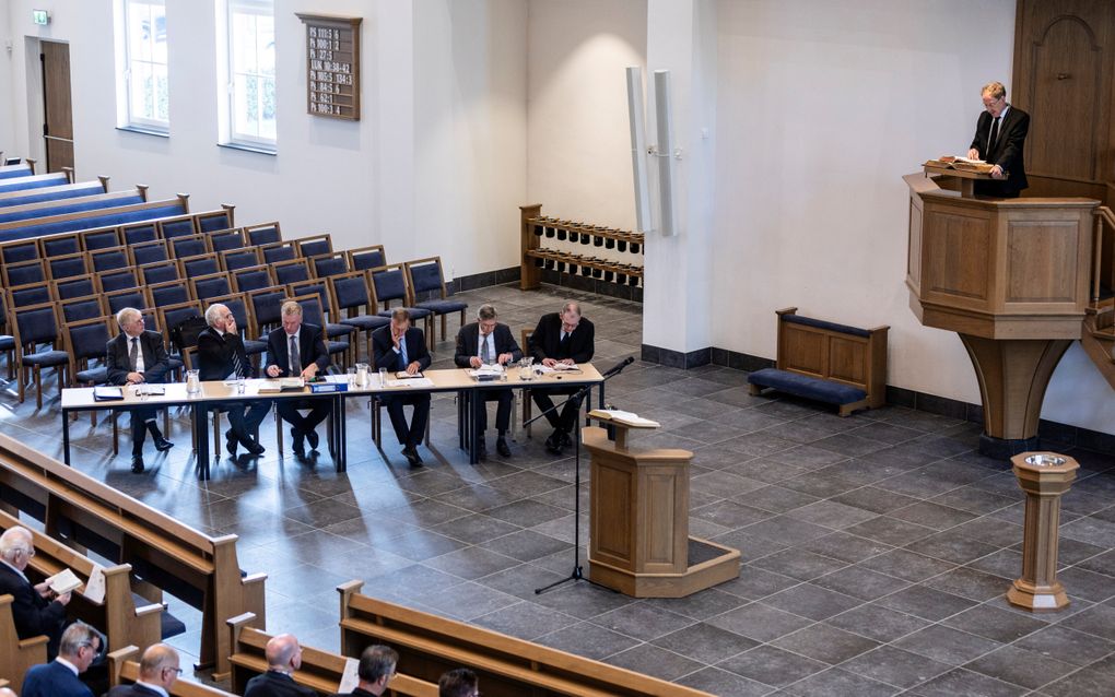 Een man op een kansel spreekt een menigte in een kerkzaal toe.