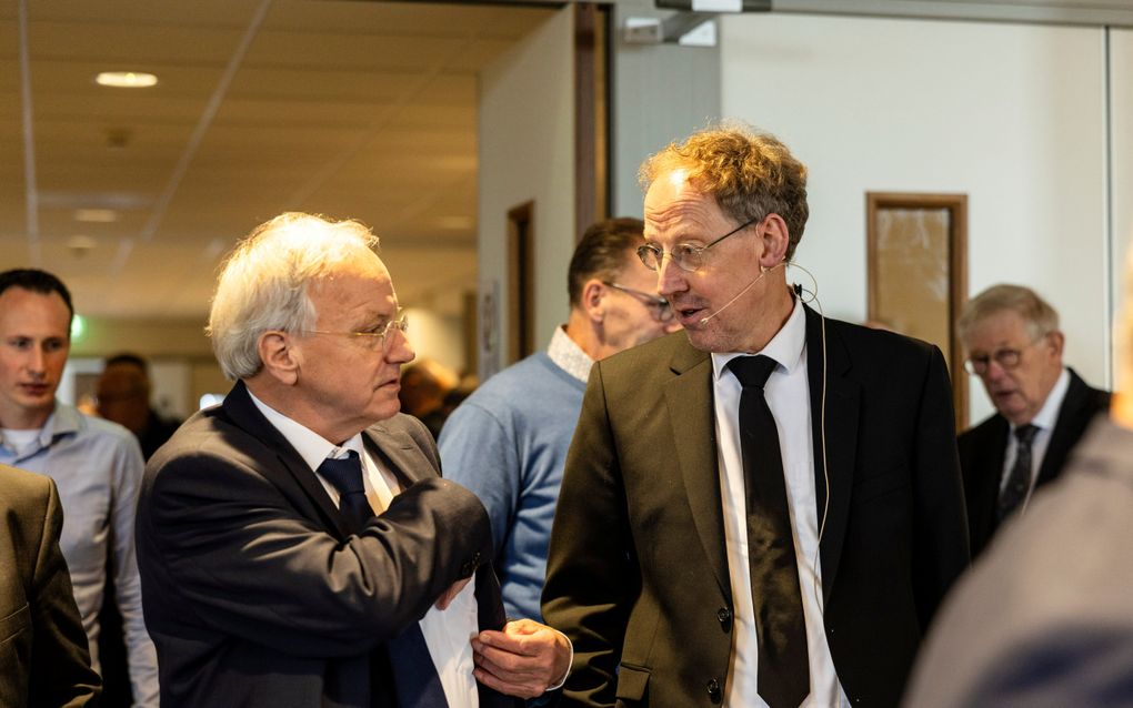 Twee mannen in zwart pak met elkaar in gesprek.