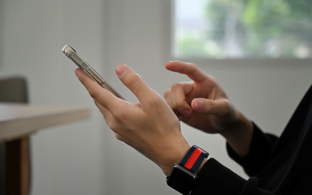 Een hand houdt een smartphone vast.