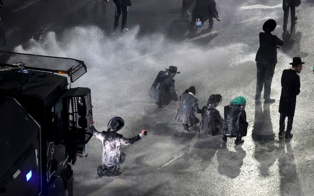 De Israëlische politie drijft protesterende ultraorthodoxe Joden uiteen tijdens een protest tegen dienstplicht voor religieuze studenten in Jeruzalem. beeld EPA< Abir Sultan