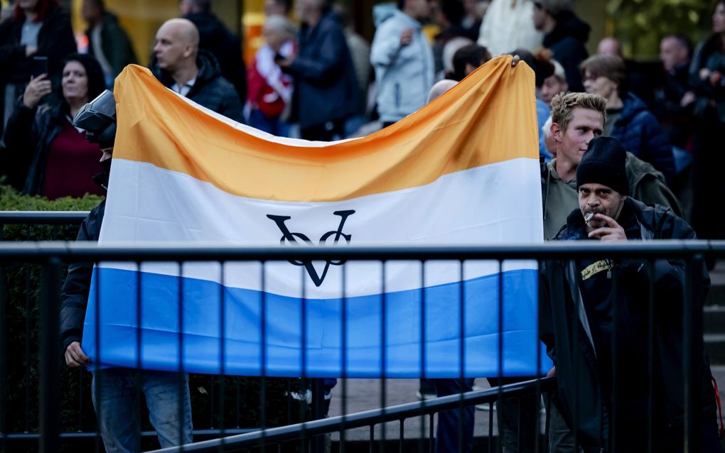 Demonstranten houden grote oranje-wit-blauwe vlag vast.