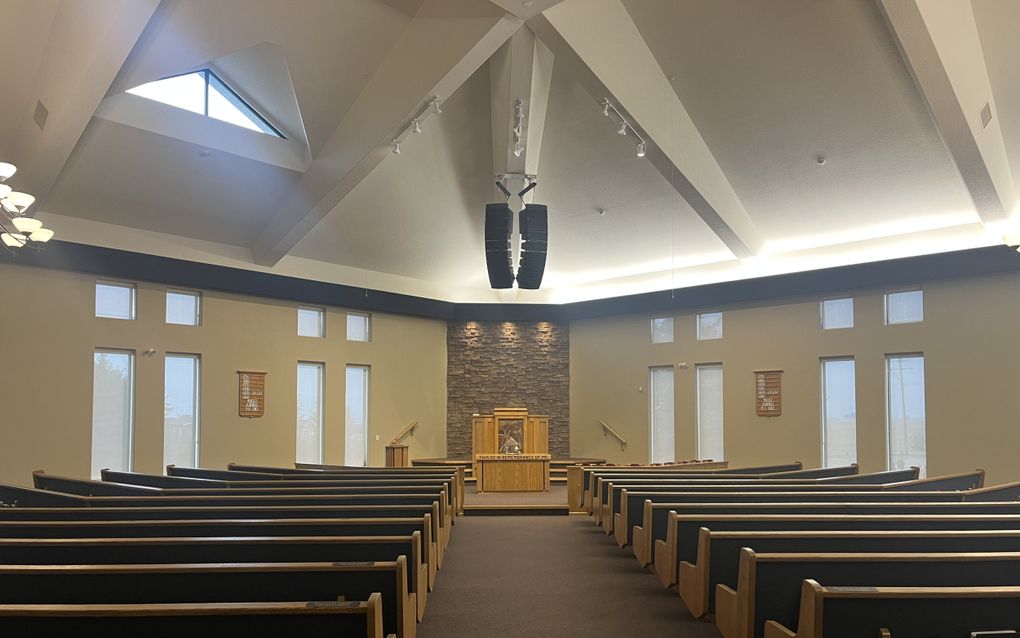 Kerkinterieur met banken en een preekstoel voorin.