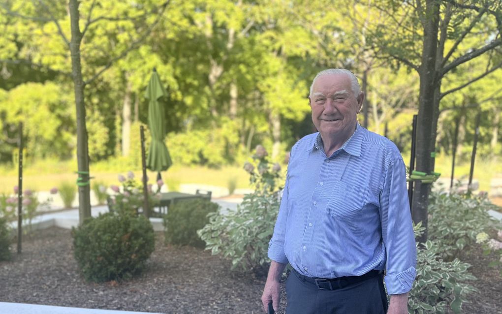 Oude man met blauw gestreept overhemd in een binnentuin.