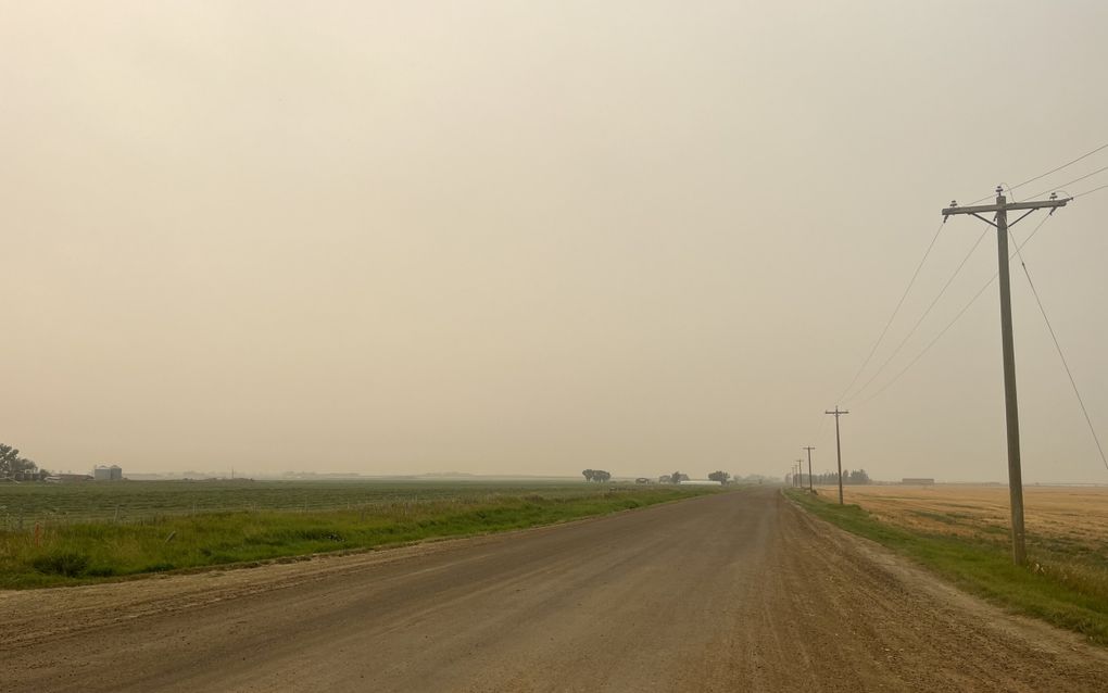 Vlak akkerlandschap met een grindweg ertussen.