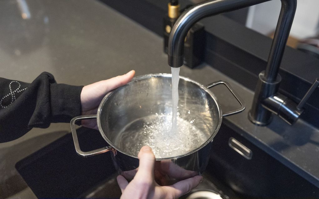 Kraan met stromend water en een pan