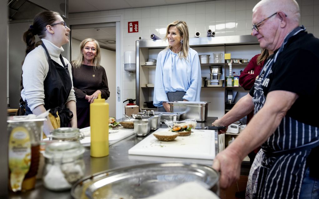 Vier vrouwen en een man rond een kookeiland. In het midden koningin Máxima.