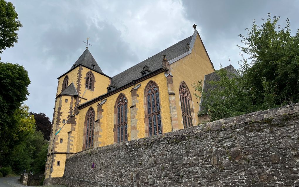 Oud kerkgebouw met een gele buitenmuur, hoge ramen.