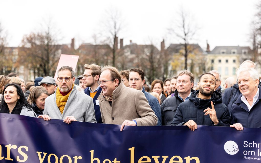 Een groep mensen loopt achter een metersbreed spandoek van de stichting Schreeuw om Leven 