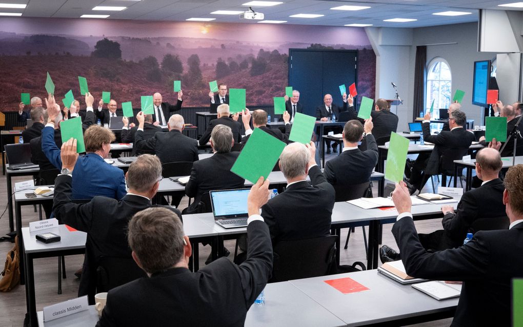 Mannen in pak achter tafels steken tijdens een stemming een groene of rode kaart omhoog.