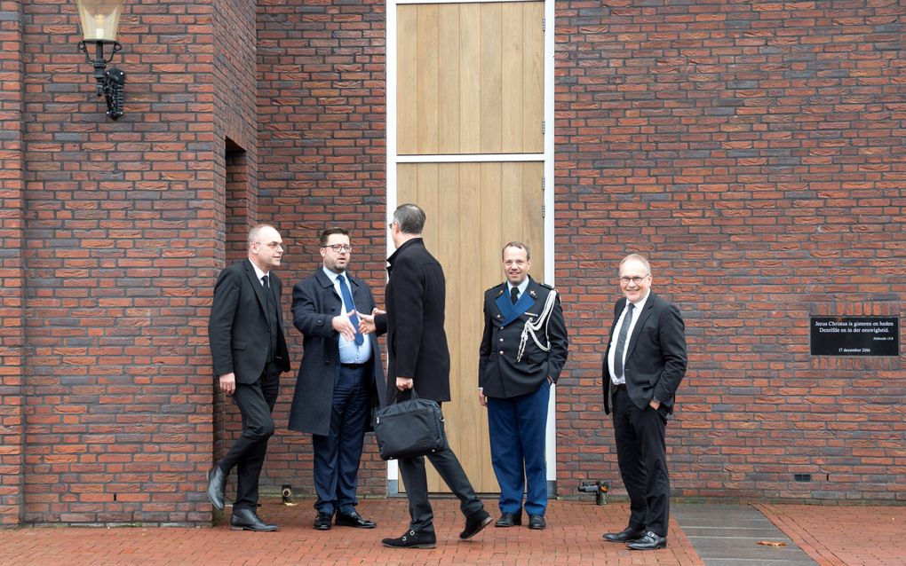 Vijf mannen staan bij een kerk.