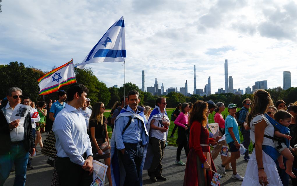 Een mars met mensen, sommigen dragen de Israëlische vlag. Op de achtergrond de wolkenkrabbers van New York.