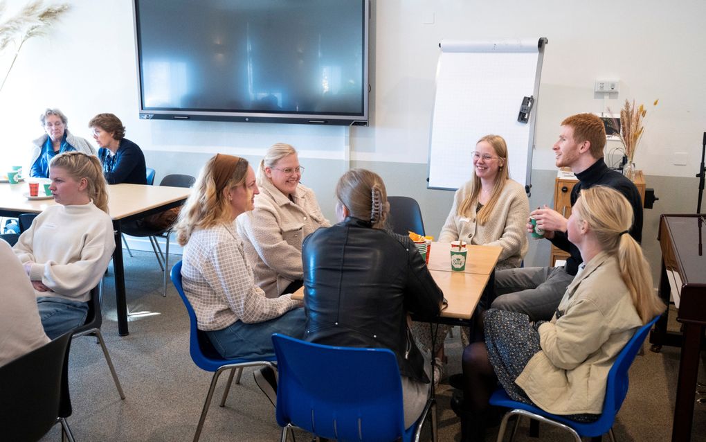 Zes mensen zitten rond een tafel. 