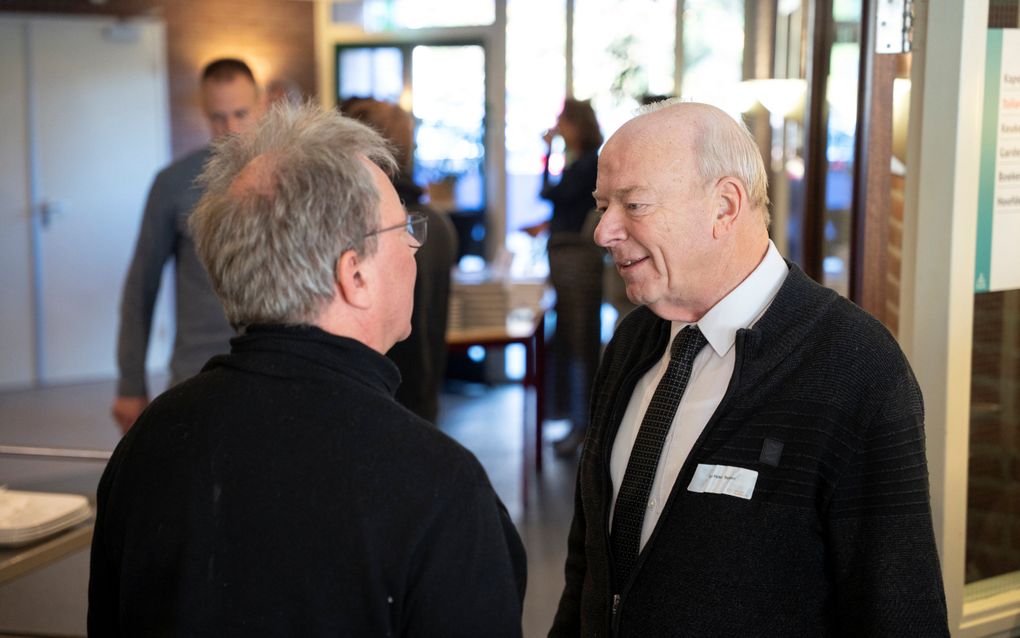 Twee mannen in donkere kleding staan met elkaar te praten.
