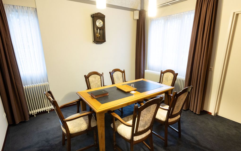 Een kamer met een houten tafel en houten stoelen met lichtgrijze bekleding.