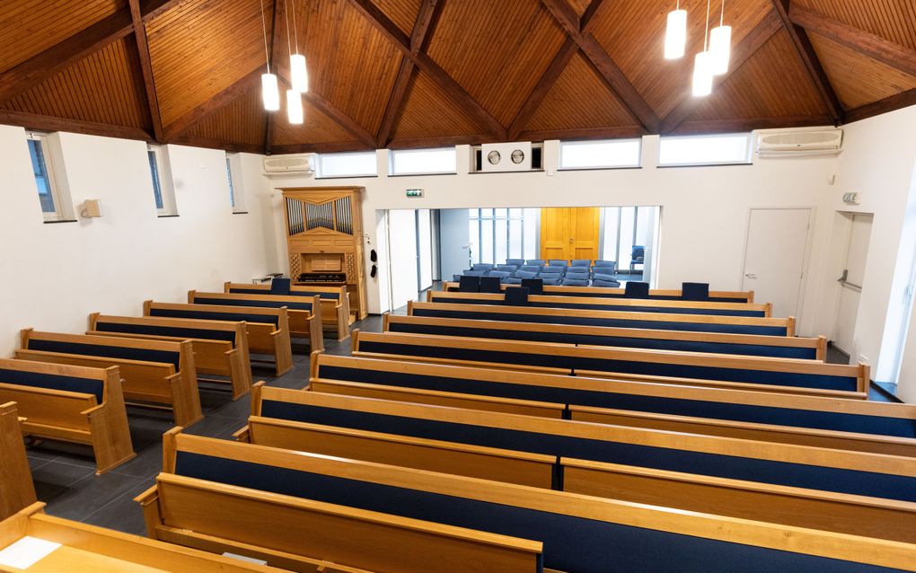 Een kerkzaal met kerkbanken, plafond van schrootjes en op de achtergrond een orgel.