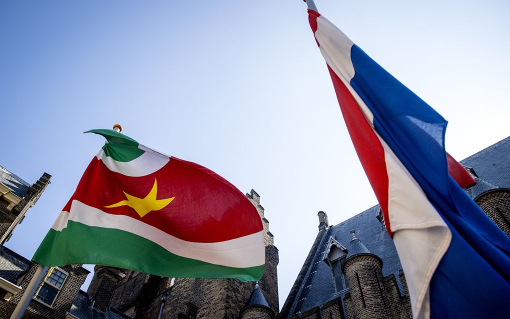De Surinaamse vlag wappert naast de Nederlandse vlag.