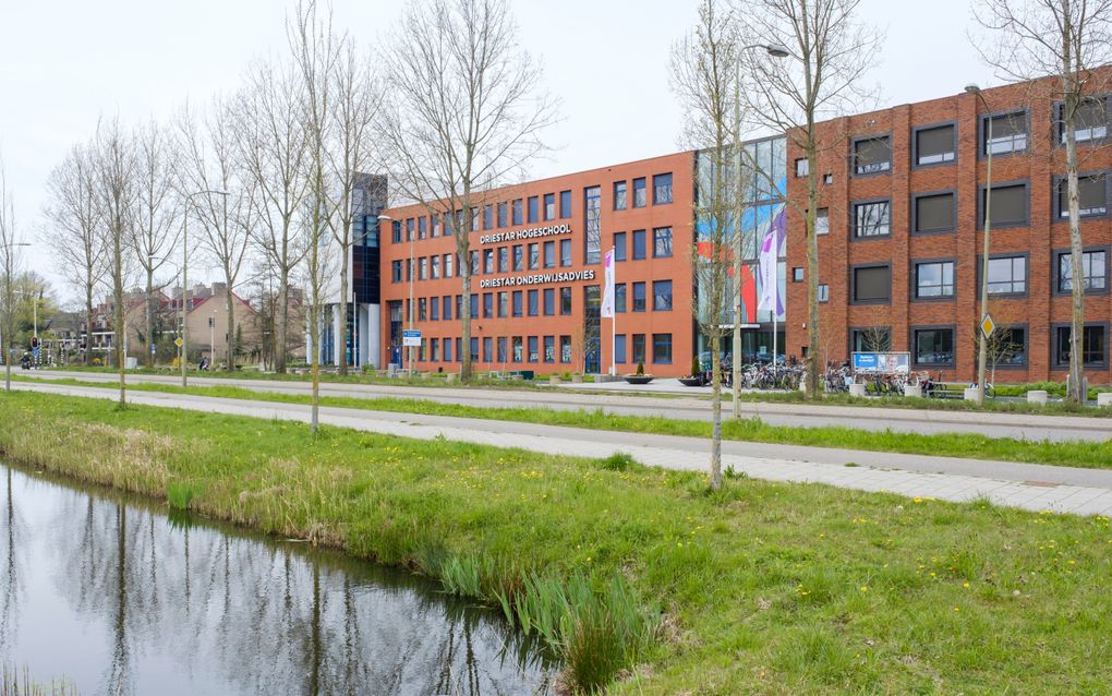 Groot schoolgebouw met kale bomen ervoor.