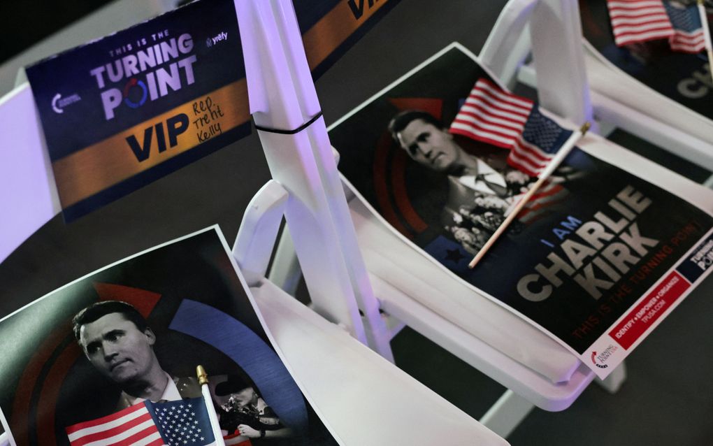 Close-up van witte klapstoelen met daaromheen een flyer met een portret van de overleden Charlie Kirk.