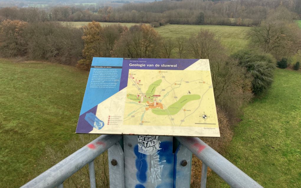 Omgevingsbord op een hooggelegen punt, met een weids uitzicht op het omringende landschap: weilanden en houtwallen. 