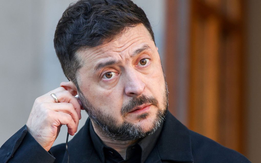 Een man in zwarte kleding houdt zijn hand bij zijn oor 