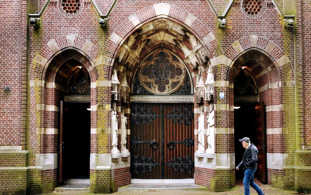 Een man met een baseballpetje op loopt langs openstaande kerkdeuren.