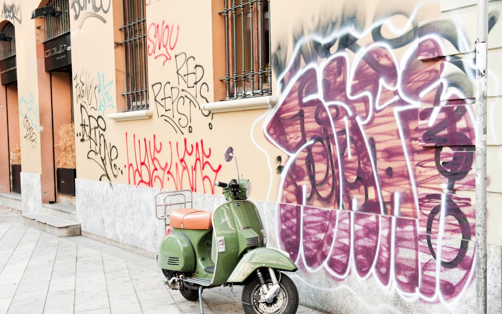 Groene scooter voor een gevel met graffiti. 