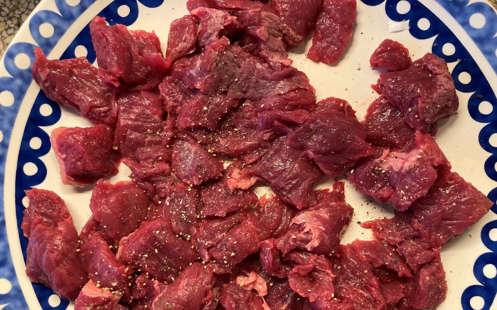 Op een blauw-wit bord liggen stukjes rauw rundvlees.