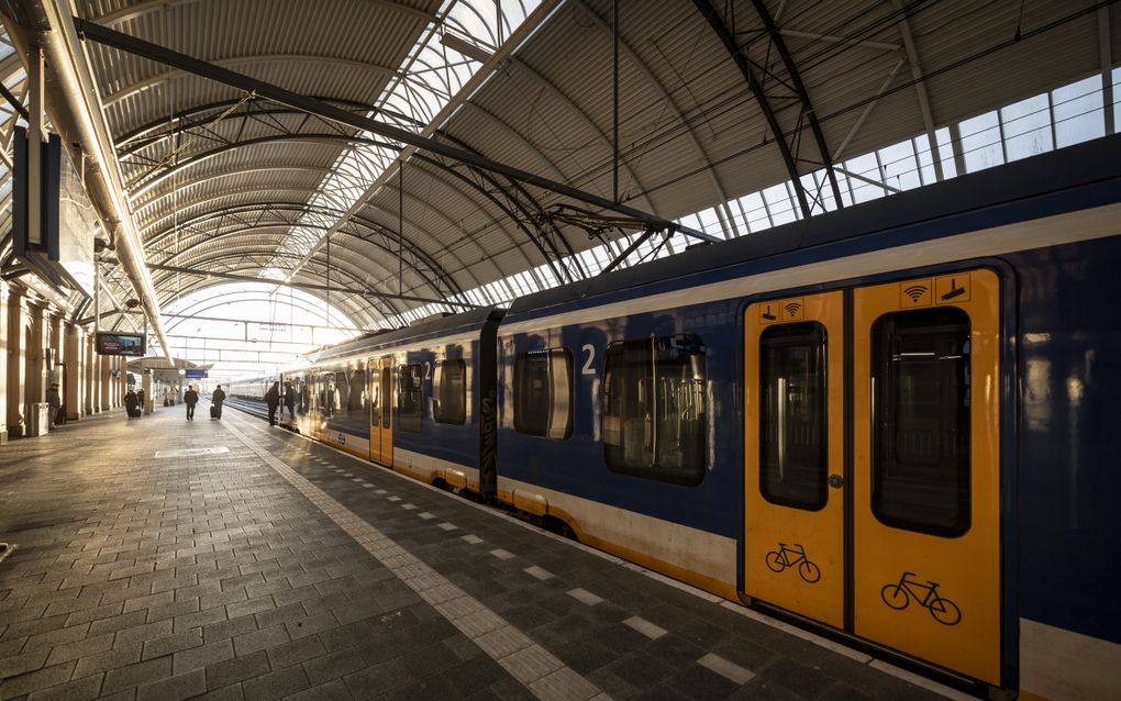 Een perron waar een trein stilstaat. De deuren van de trein zijn gesloten en er lopen enkele mensen op het perron. 