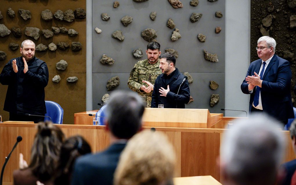 Oekraïense mannen staan in het kabinetsvak van de plenaire zaal van de Tweede Kamer, met op de voorgrond Kamerleden. Er wordt geapplaudiseerd.