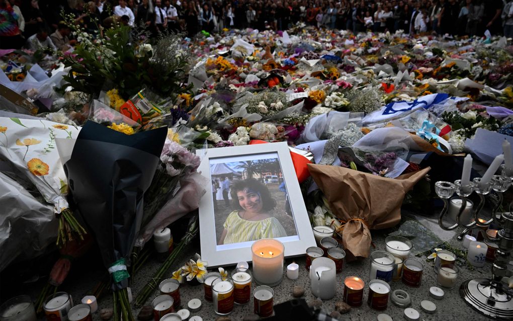 Ingelijste foto van meisje ligt naast grote hoeveelheid kaarsjes en bloemen op straat.