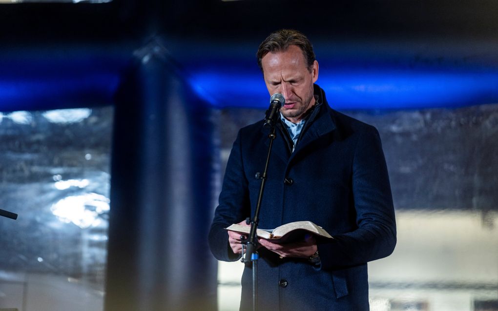 Man in donkere jas heeft een boek in zijn hand.