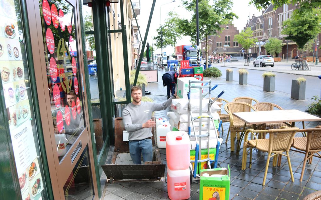 Damian Besselsen geeft de zakken meel en blikken olie door aan collega Fons Molen in de kelder onder de grond. beeld Sjaak van de Groep