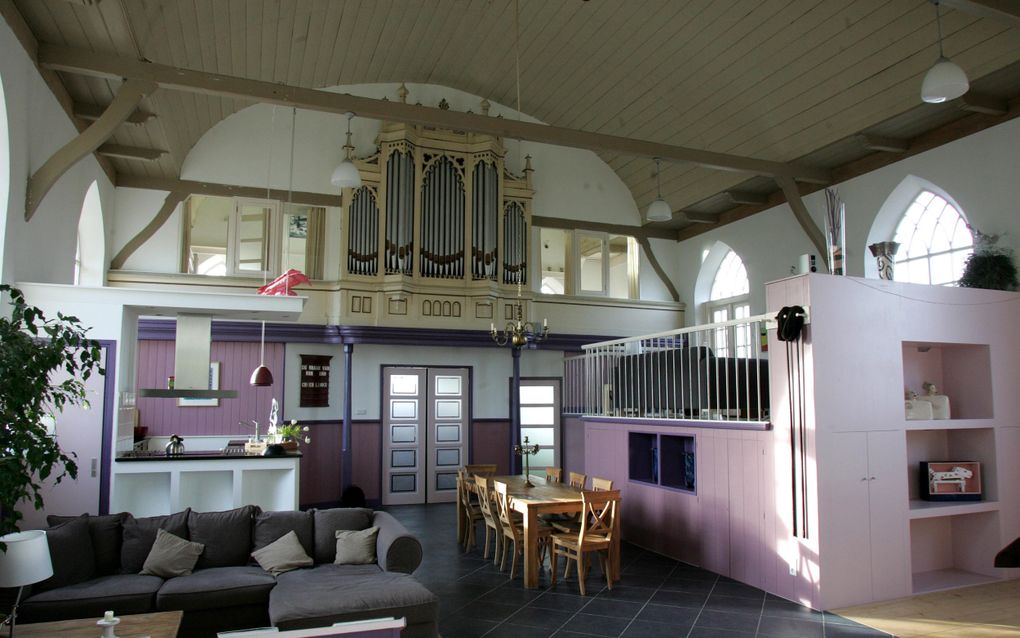 In een voormalige kerk, met orgel, staan een zitbank en een eettafel.