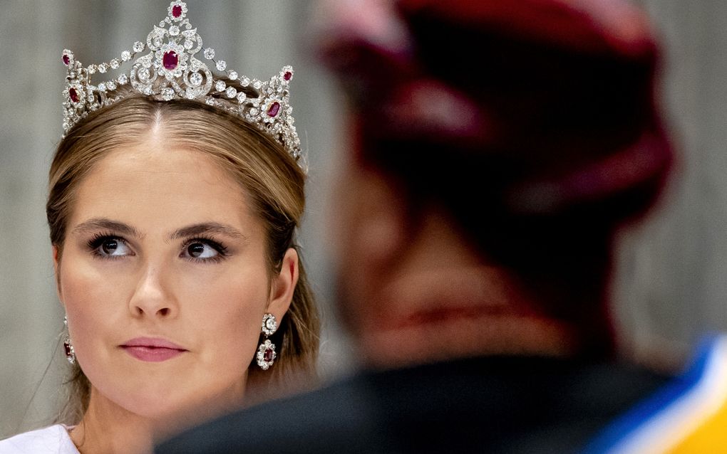 Vrouw met tiara op het hoofd. Voor haar zit iemand met een tulband.