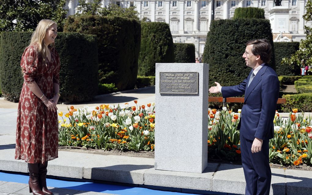 Jonge vrouw staat bij een plaquette met daarachter bloeiende tulpen. Een man wijst naar de plaquette.