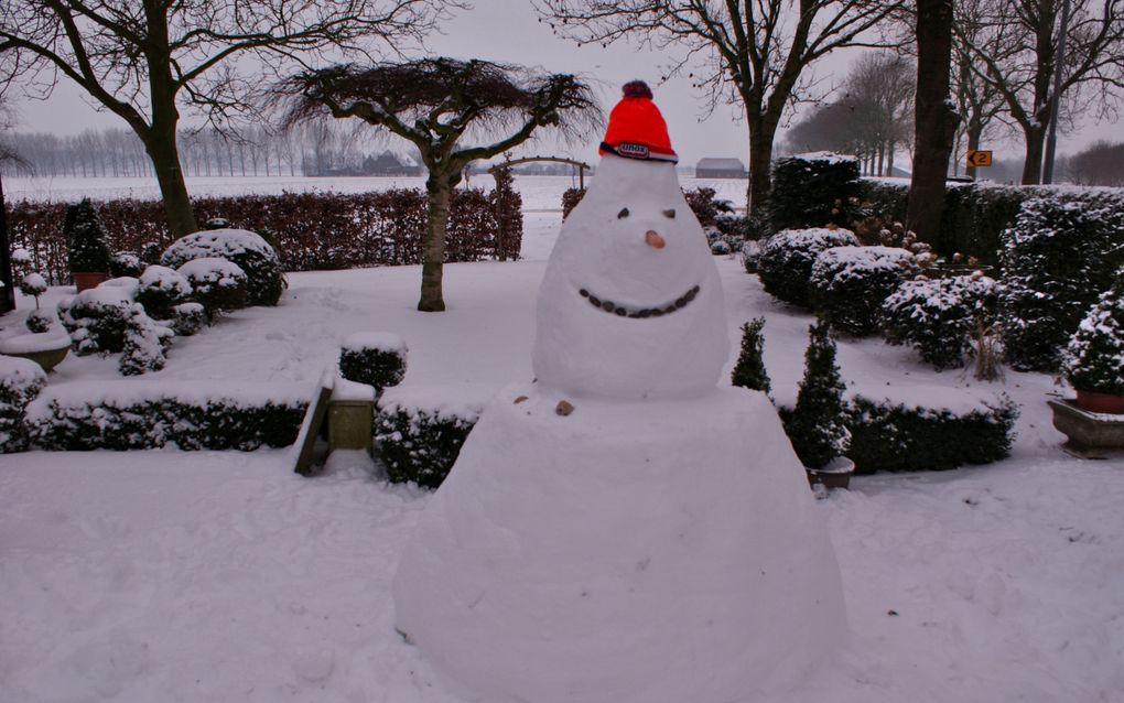 Sneeuwpop in een tuin, met een oranje Unox-muts op.