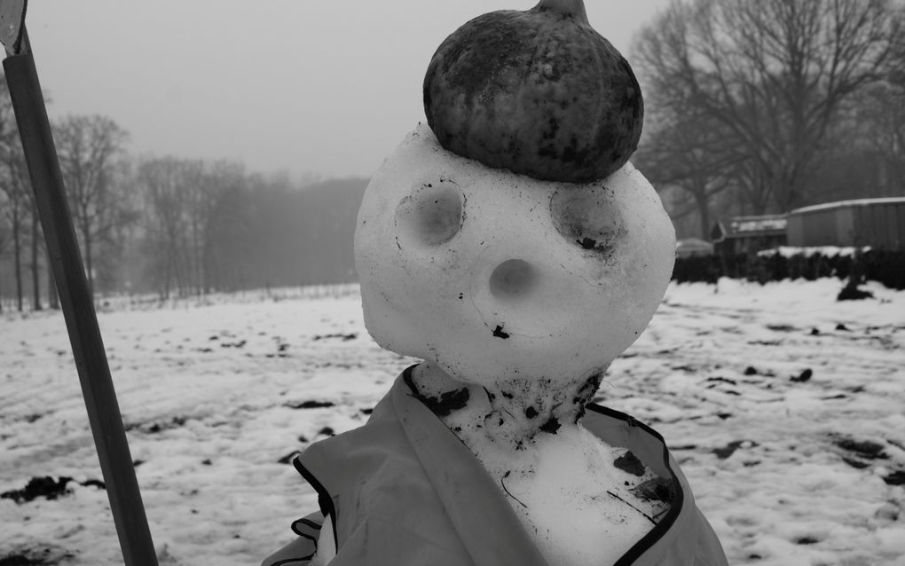 Smeltende sneeuwpop met een pompoen als pet. Zwart-witfoto.