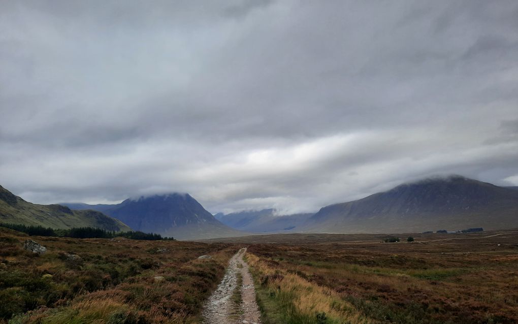 Steenachtig pad dat over bruin heidelandschap richting een vallei loopt met grijze laaghangende bewolking.