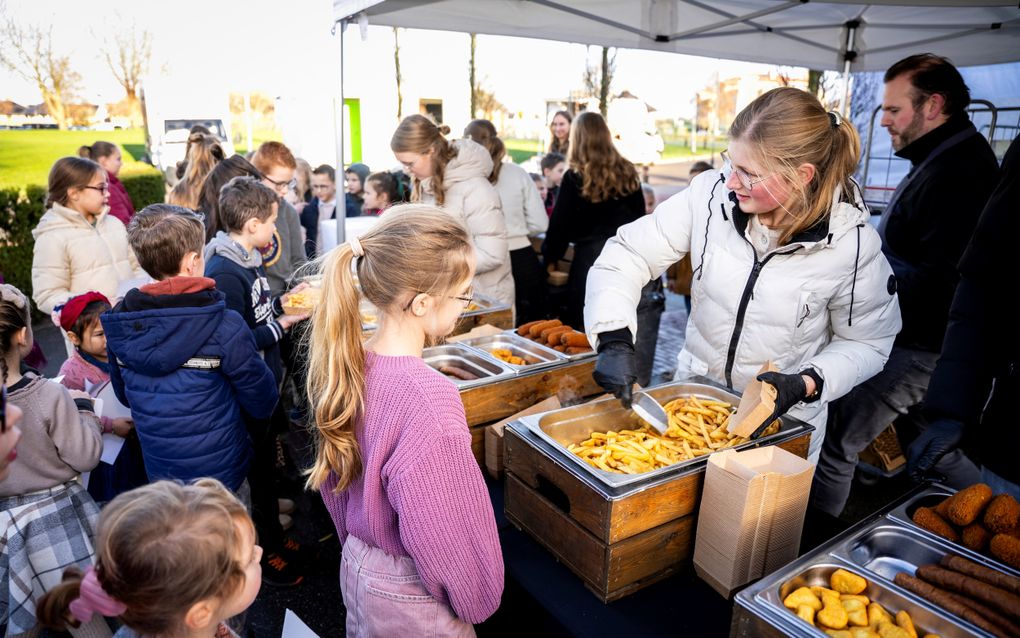 Meisje schept patat in een bakje.