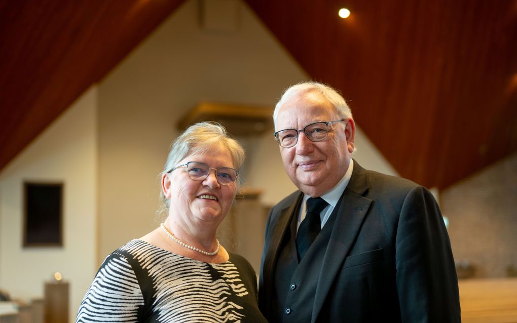 Man in driedelig zwart pak, samen met zijn vrouw. Beiden lachen.