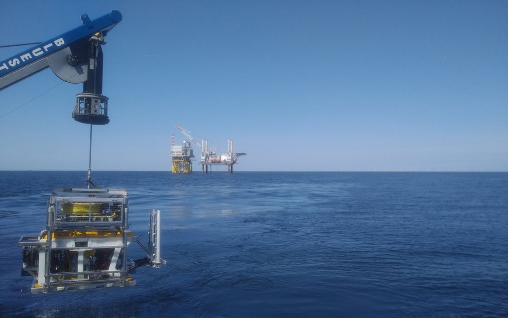 Een kraan zet op volle zee een onderwaterrobot vol met sensoren overboord. Vervolgens vaart deze met het schip in lengterichting over de kabel en legt de positie daarvan exact vast. beeld Stema