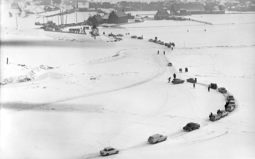 Zwart-witte luchtfoto waarbij een sliert auto’s te zien is die over een bevroren wit meer rijden. Verschillende passagiers zijn uitgestapt.