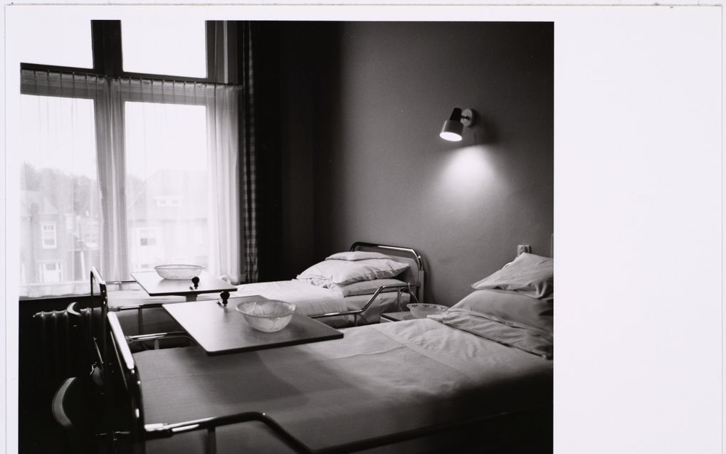 Zwart-witfoto van twee strak opgemaakte ziekenhuisbedden in een kamer.