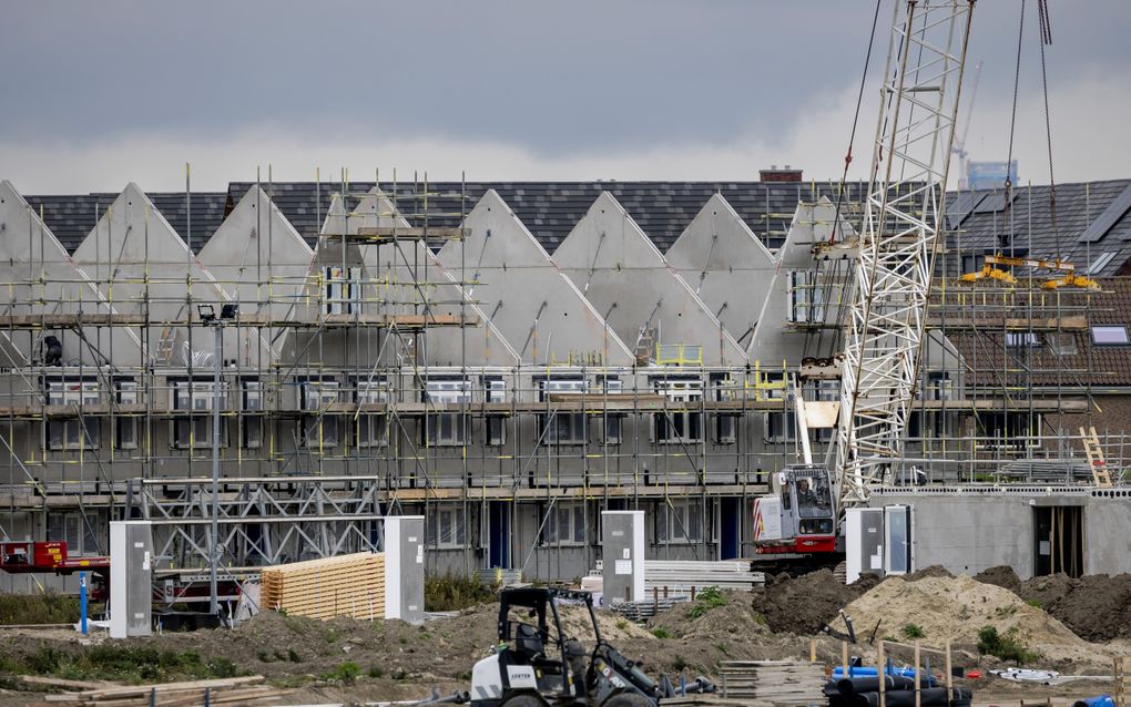 Rijtjeshuizen in aanbouw met op de voorgrond een shovel en een hijskraan.