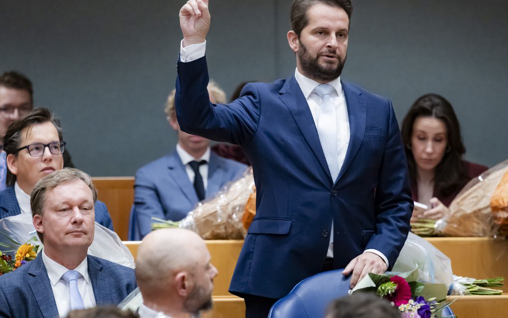 Man met baard in blauw kostuum legt de eed af.