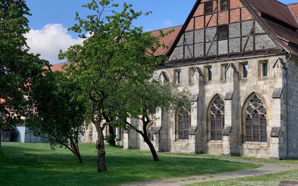 Kerkgebouw van de buitenkant. Ervoor een grasveld met bomen.