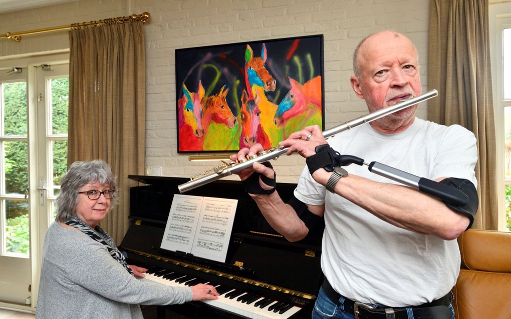 Henk Bruijstens gebruikt twee zogeheten antitremorortheses als hij dwarsfluit speelt. Zijn partner Jeanne Caspers begeleidt hem op de piano. beeld Erald van der Aa