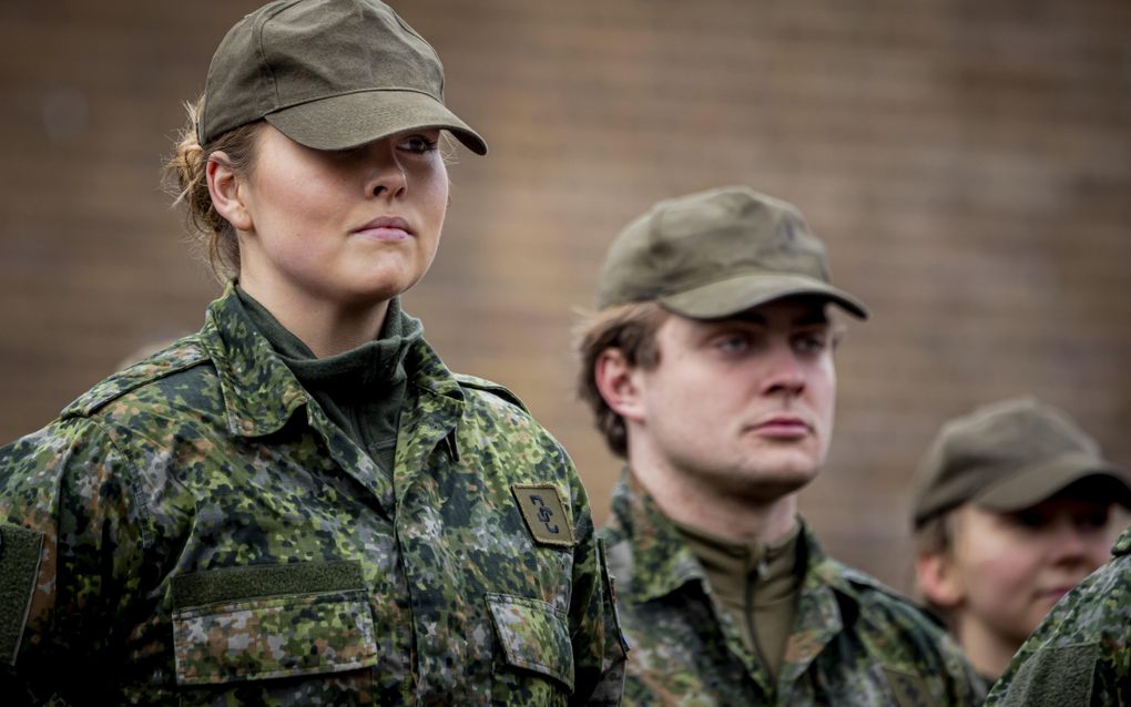Jonge vrouw in militair uniform en een groene pet op.
